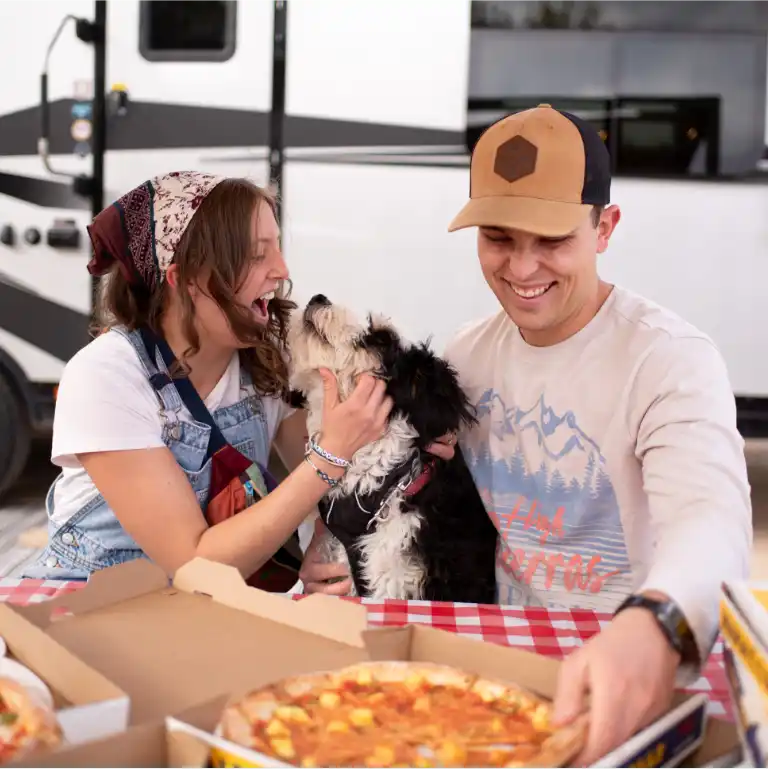Couple and dog eating pizza